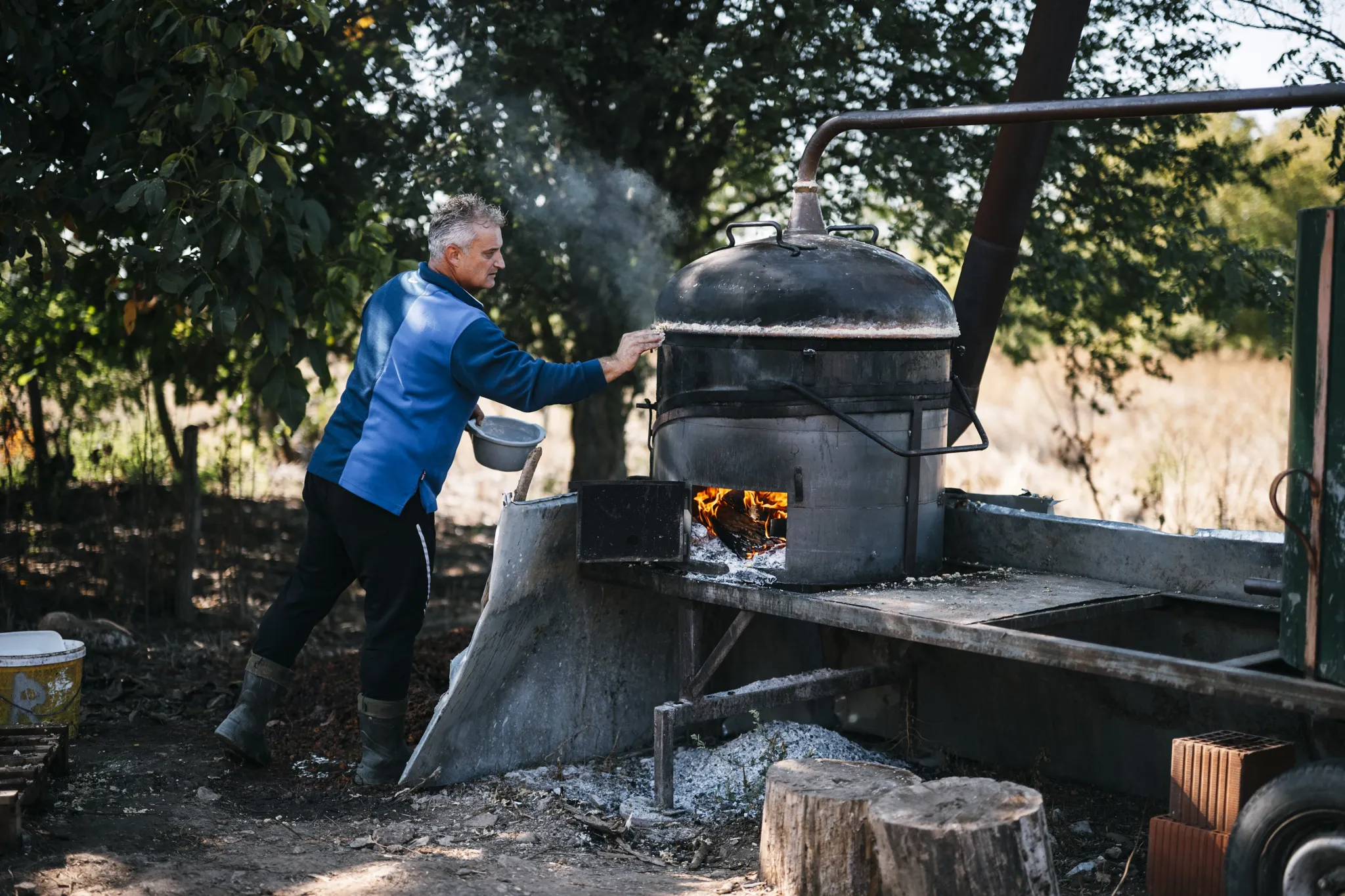 Clear rakija running from the copper still into a yellow bowl