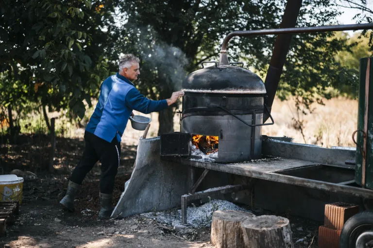 Clear rakija running from the copper still into a yellow bowl