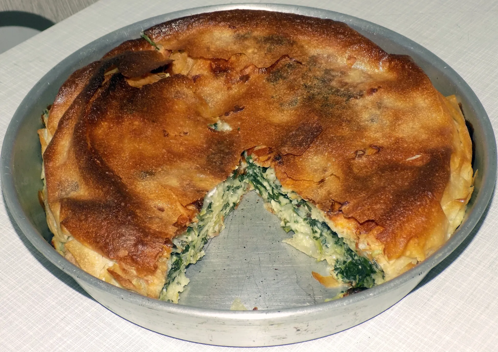 A round home-made pita with spinach and cheese, cut open on the table
