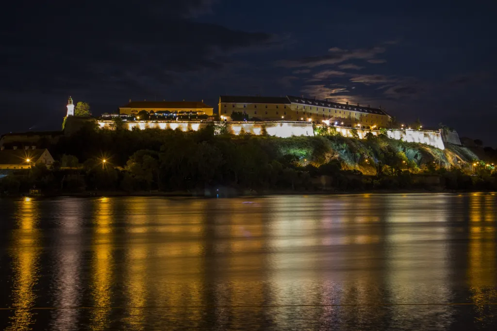 Petrovaradin Fortress lit up at night and reflected in the Danube