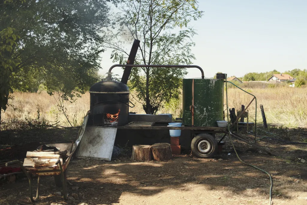 A traditional rakija still steaming in a village farmyard