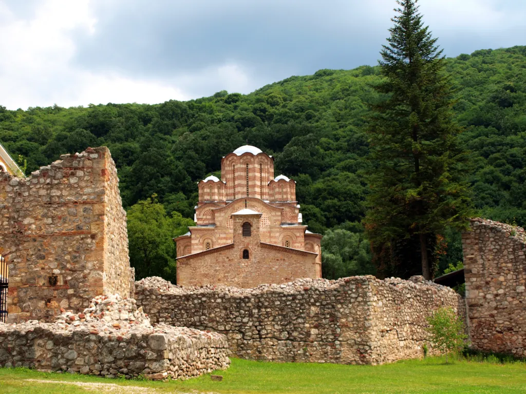 The brick-and-stone church of Ravanica Monastery seen over its ruined defensive walls