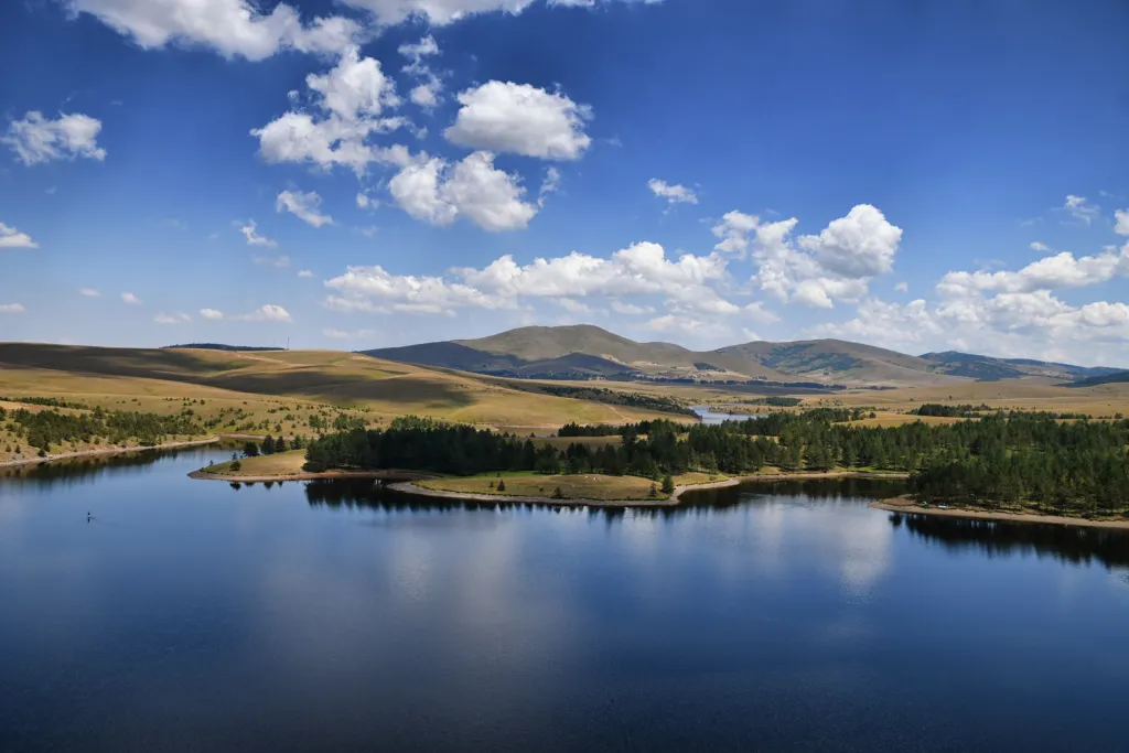 Ribnica Lake mirroring the sky between pine woods and the rolling Zlatibor plateau