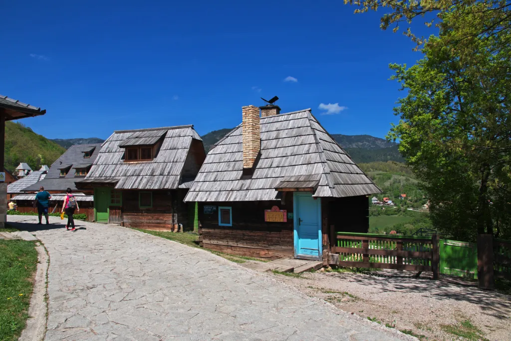 Log houses with wooden shingle roofs along a stone lane in Drvengrad, Mokra Gora