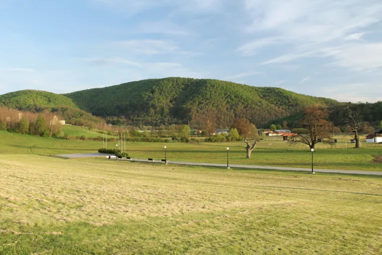 The open meadow of the Takovo uprising memorial complex below the green Šumadija hills