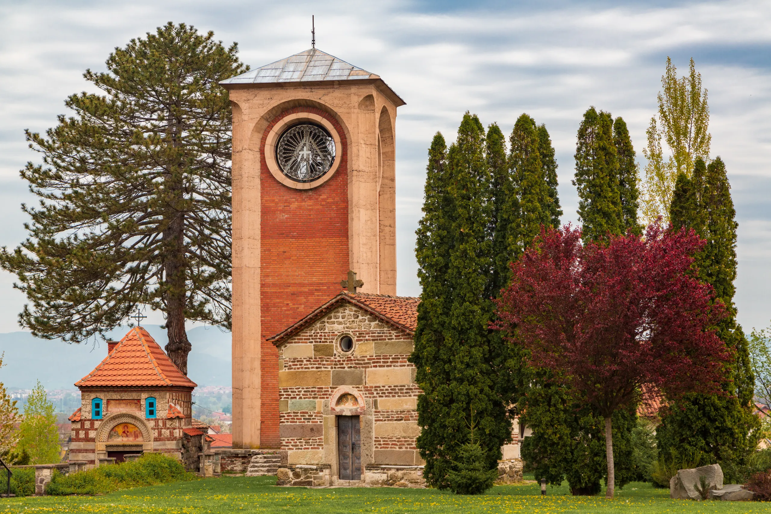 The red bell tower and church of Žiča Monastery among trees